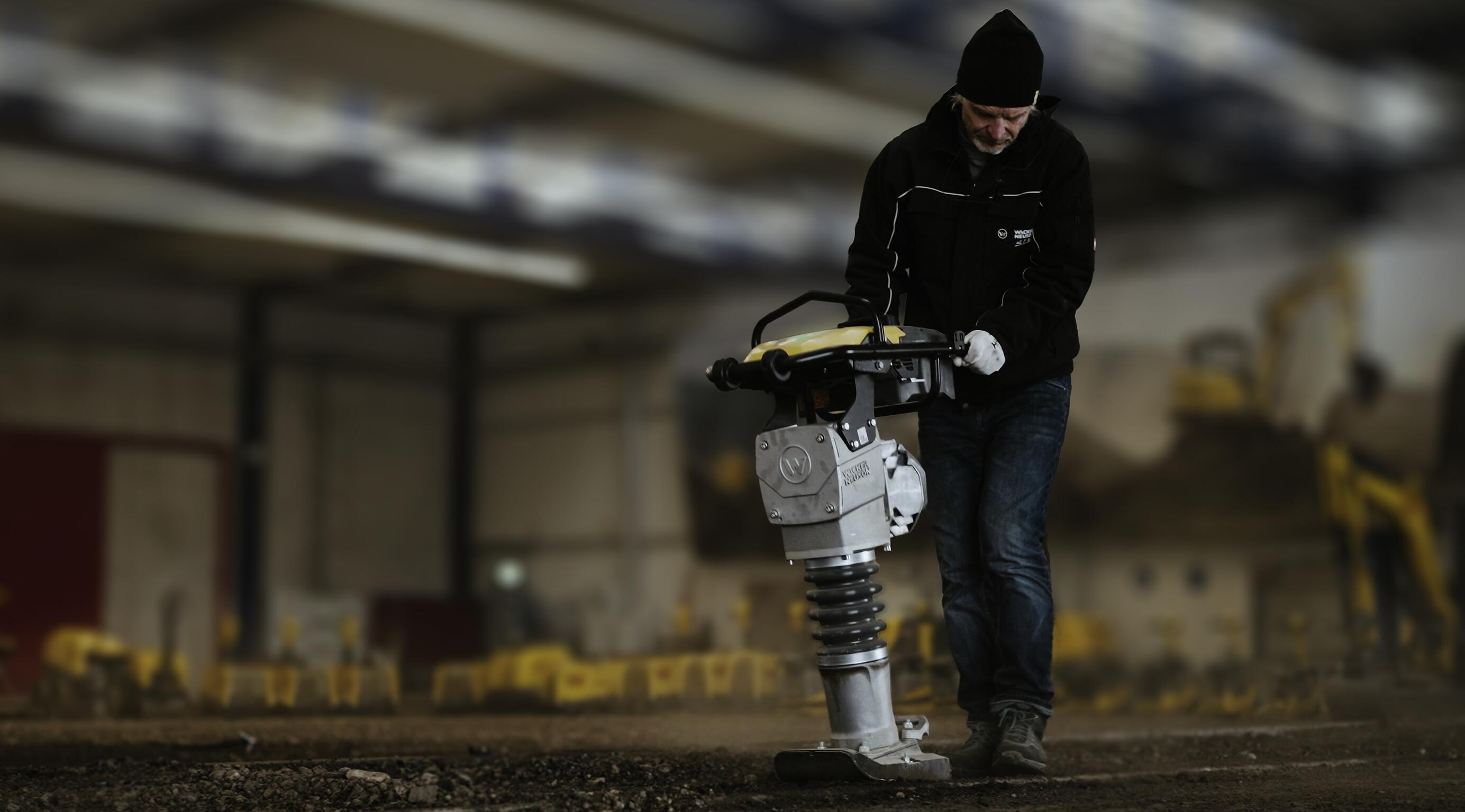 Trabajador manejando un apisonador para la compactación del suelo en un entorno de formación en construcción en interiores