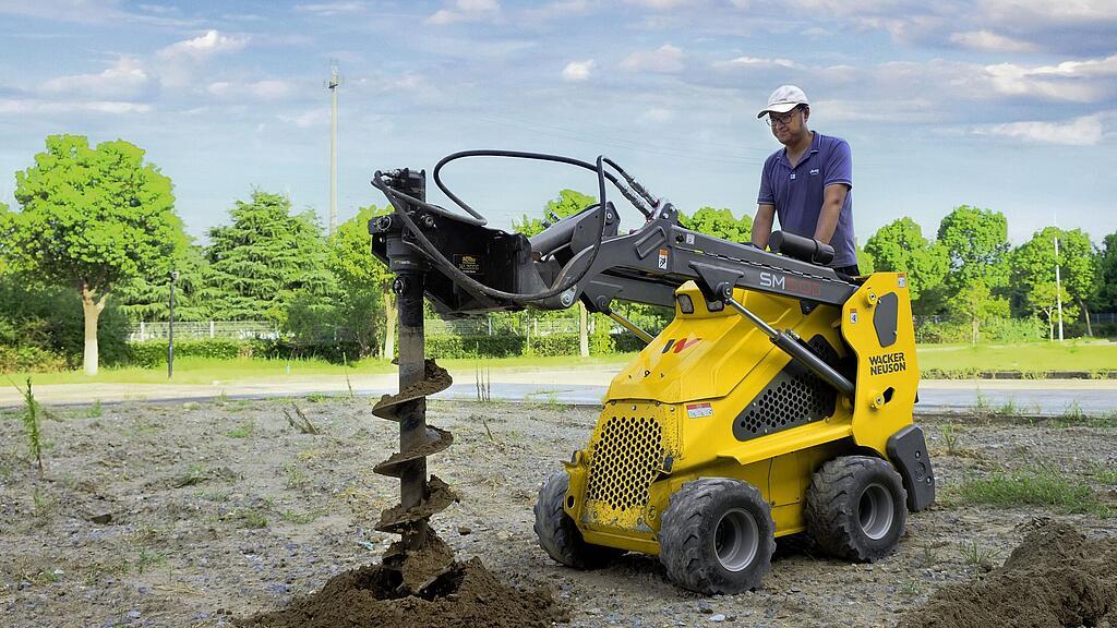 Minicargadora sobre ruedas con sinfín en acción