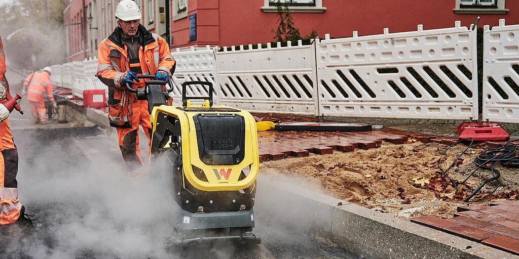 Obrero de la construcción trabajando con una plancha vibratoria en una obra del centro de la ciudad