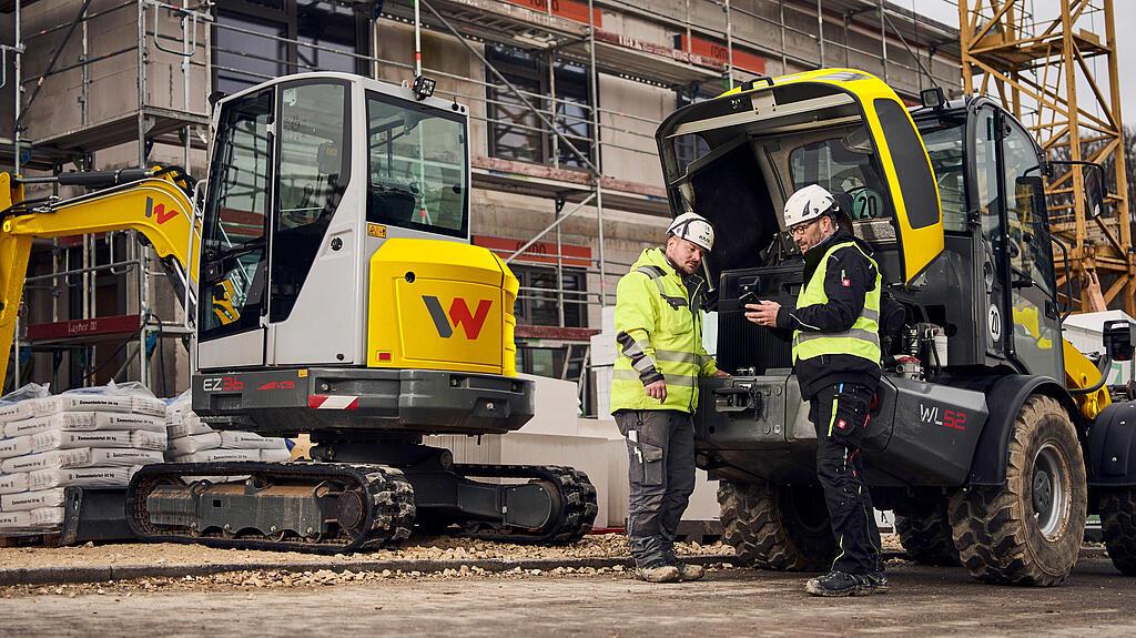 two persons stand in front of wacker neuson machines